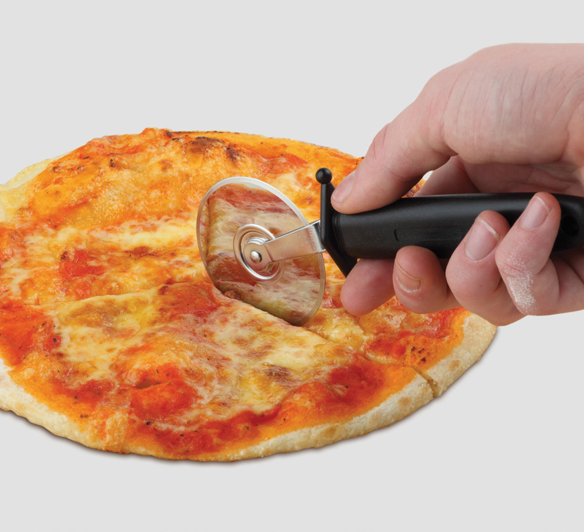 Roulette à pizza en inox découpant une pizza