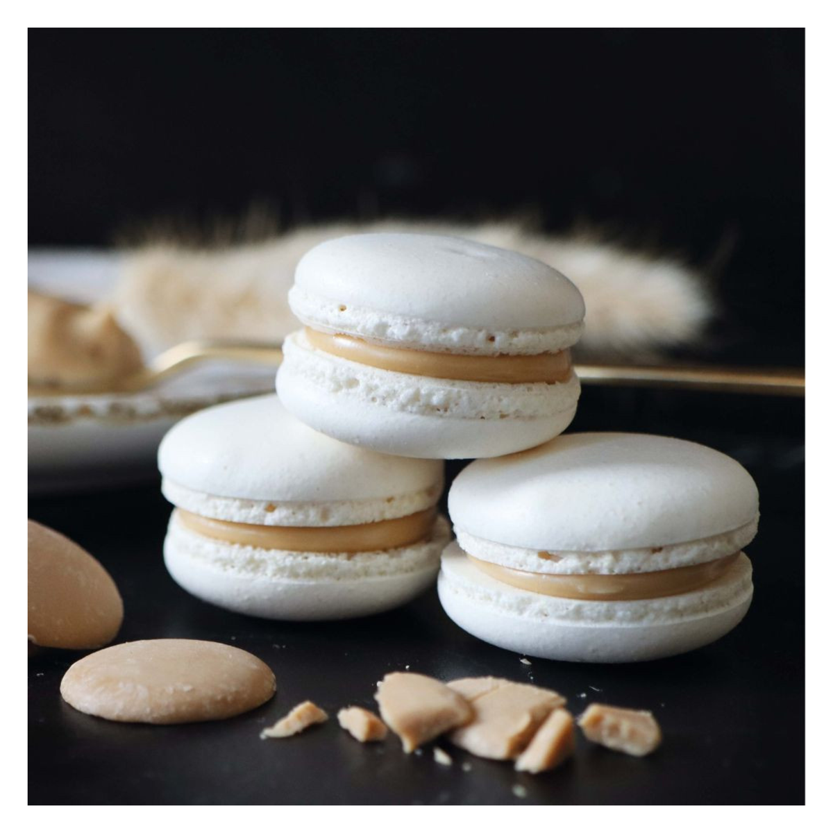 Macarons blancs garnis de crème sur fond noir