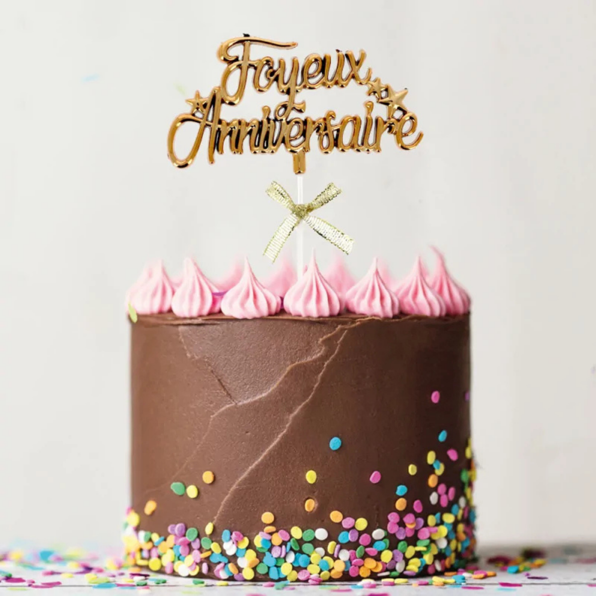 Cake topper doré « Joyeux Anniversaire » avec nœud décoratif sur gâteau d’anniversaire au chocolat