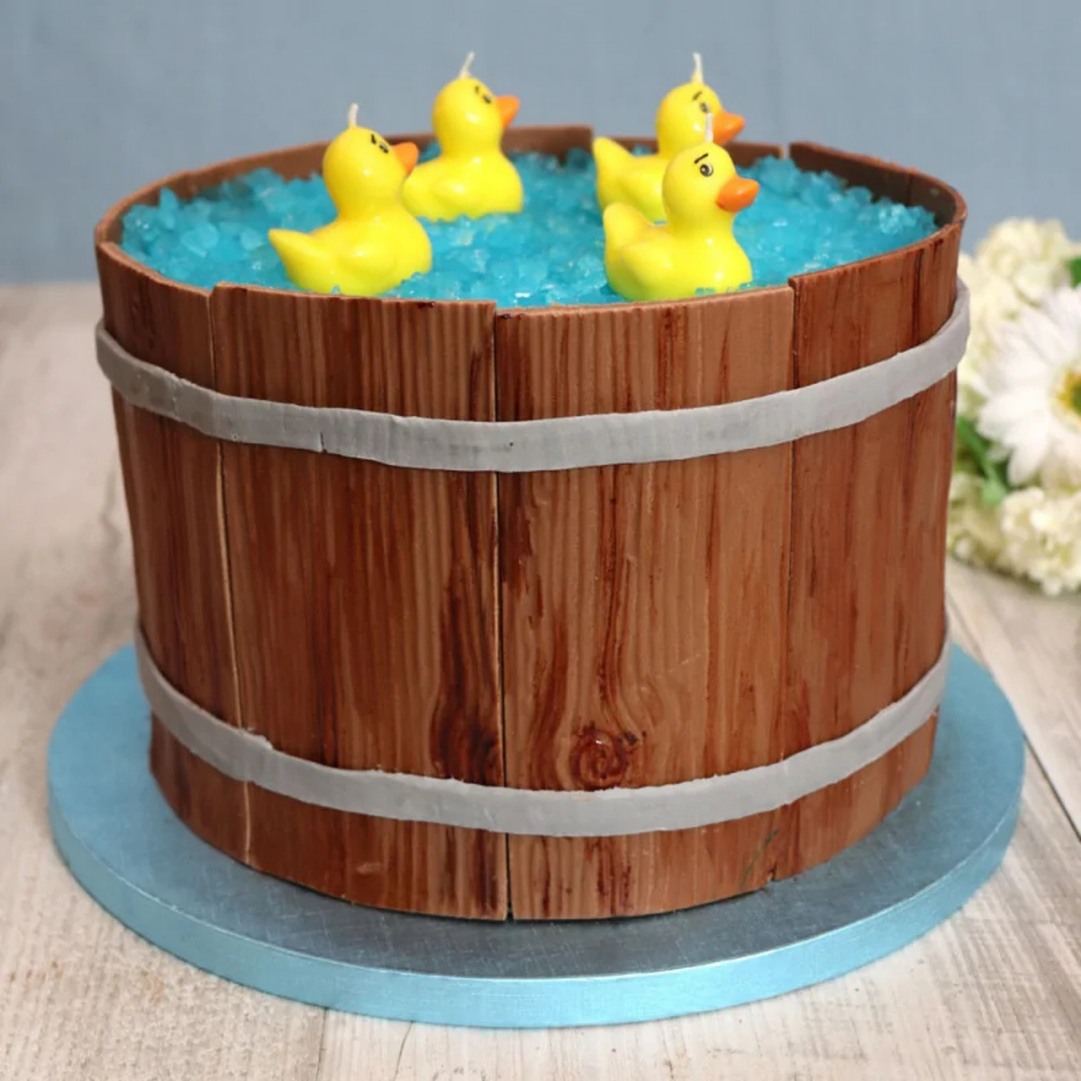 Gâteau décoratif en forme de tonneau avec canards présenté sur un plateau rond bleu