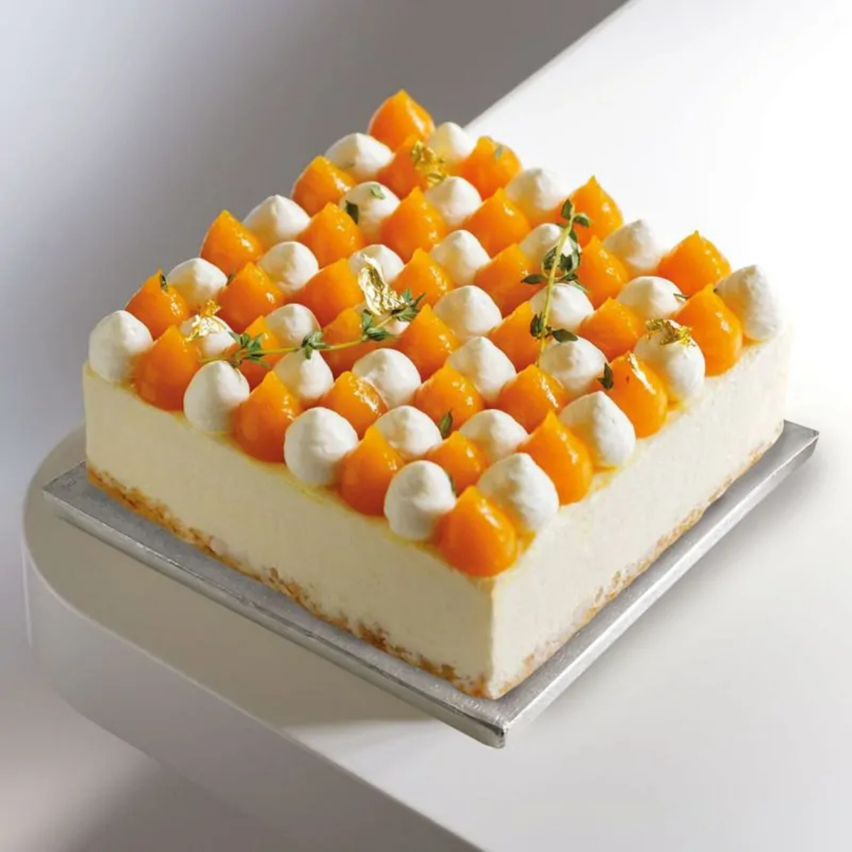 Gâteau carré décoré aux agrumes présenté sur un plateau de présentation argenté