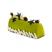 Bûche de Noël pâtissière verte décorée d'étoiles en chocolat noir, de cerises et de copeaux de chocolat blanc