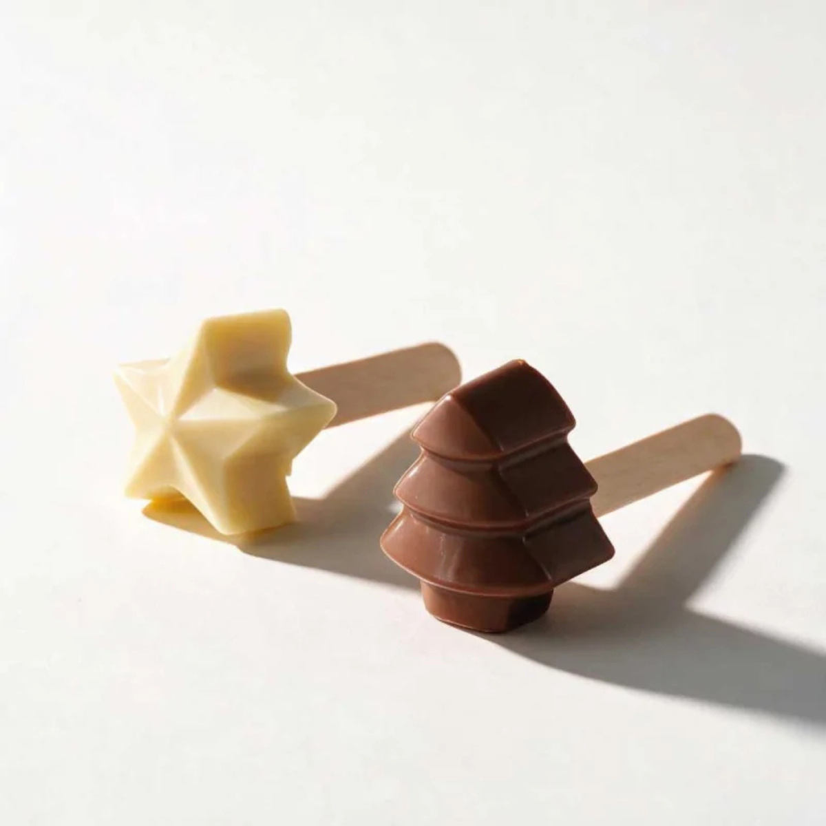 Présentation des sucettes de Noël en chocolat réalisées avec le moule PatisDécor, motifs étoiles et sapins en chocolat.
