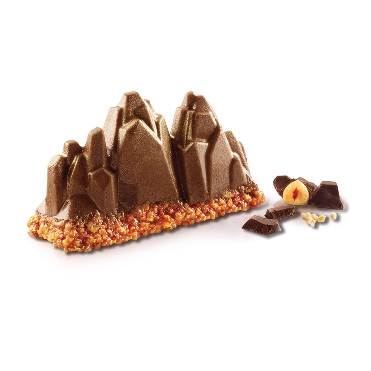 Entremets au chocolat en forme de montagnes rocheuses aux sommets anguleux, posé sur une base croustillante aux noisettes, avec morceaux de chocolat et noisette en décoration.