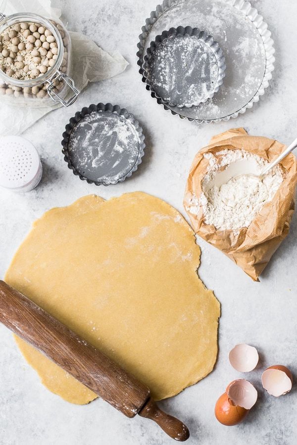 Pâte à tarte étalée au rouleau avec moules à tartelettes et farine